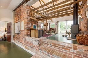 A spacious living area with exposed brick walls, a large fireplace, and a view of the outdoors.