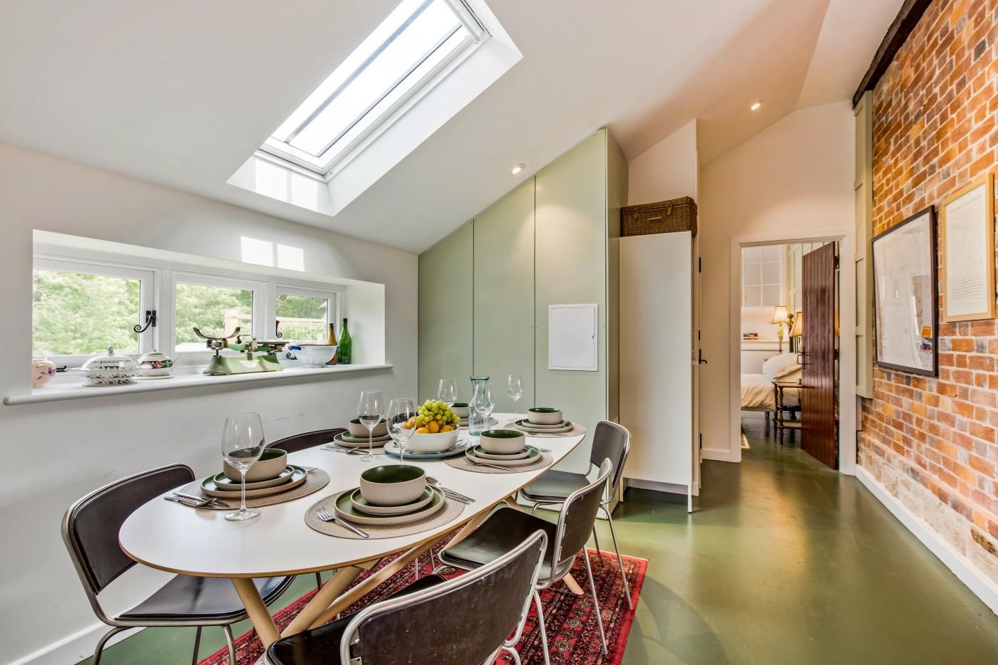 A dining area with a high ceiling, skylight, and a view of the outdoors.