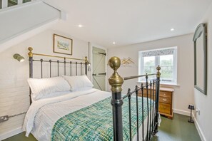 Une chambre à coucher avec un lit, une fenêtre, une commode et un escalier.