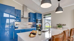 Eine moderne Küche mit blauen Schränken, einer weißen Kücheninsel und einem Essbereich mit Ledersesseln.