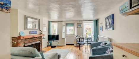Een woonkamer met een open haard, televisie en zithoek.