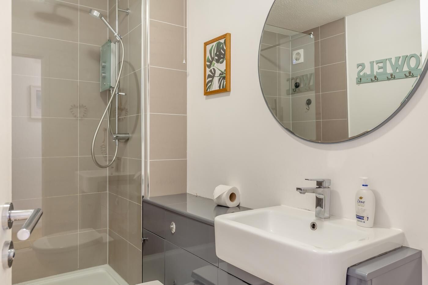 Une salle de bain moderne avec une douche à parois de verre, un lavabo blanc et un miroir.