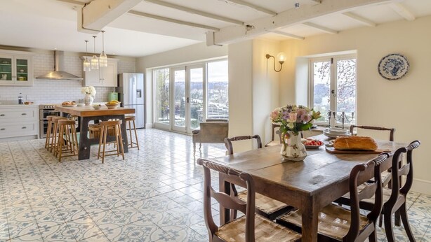 A spacious kitchen with a large island, a dining area with a wooden table, and a view through the glass doors. - 4 Bed in Pateley Bridge (oc-s34135) (Pateley Bridge)