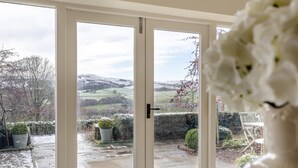 A room with a sliding glass door leading to a garden with a stone pathway and potted plants. - 4 Bed in Pateley Bridge (oc-s34135) (Pateley Bridge)