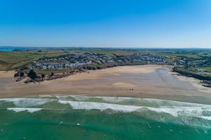 Ein Luftbild einer Küstenstadt mit Sandstrand, klarem, blauem Wasser und einem Wohngebiet mit Häusern.