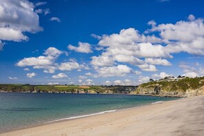 Een kuststrand met heldere lucht en enkele wolken.