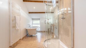 Un baño moderno con cabina de ducha de vidrio, bañera independiente y radiador.