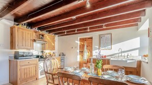 Cocina con armarios de madera, una mesa de comedor preparada para cuatro personas y vistas al exterior.