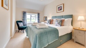 A bedroom with a bed, a chair, a nightstand, a lamp, and a window with curtains. - 2 Bed in Alnwick (oc-nb1986) (Howick)