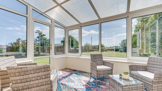 A sunroom with large windows, wicker furniture, and a patterned rug. - 2 Bed in Alnwick (oc-nb1986) (Howick)