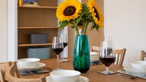 A dining table with a vase of sunflowers, wine glasses, and white plates. - 2 Bed in Alnwick (oc-nb1986) (Howick)