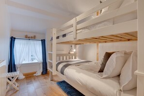 Ein Schlafraum mit Etagenbetten, einem Fenster, einem Heizkörper und einem kleinen Tisch.