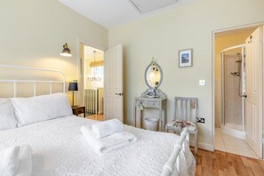 Een slaapkamer met een bed, een kapstok, een spiegel en een douche.