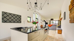 Una cocina moderna con una isla central, un comedor con sofá y vistas al exterior.