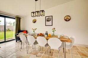 A dining area with a wooden table, white chairs, and a view of the backyard through a glass door. - 5 Bed in Briston (oc-1875) (Briston)