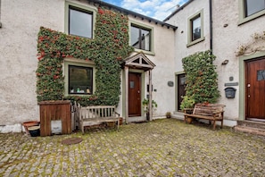 A building with a cobblestone courtyard, wooden benches, and a small wooden gate. - 2 Bed in Bassenthwaite (oc-ld171) (Bassenthwaite)
