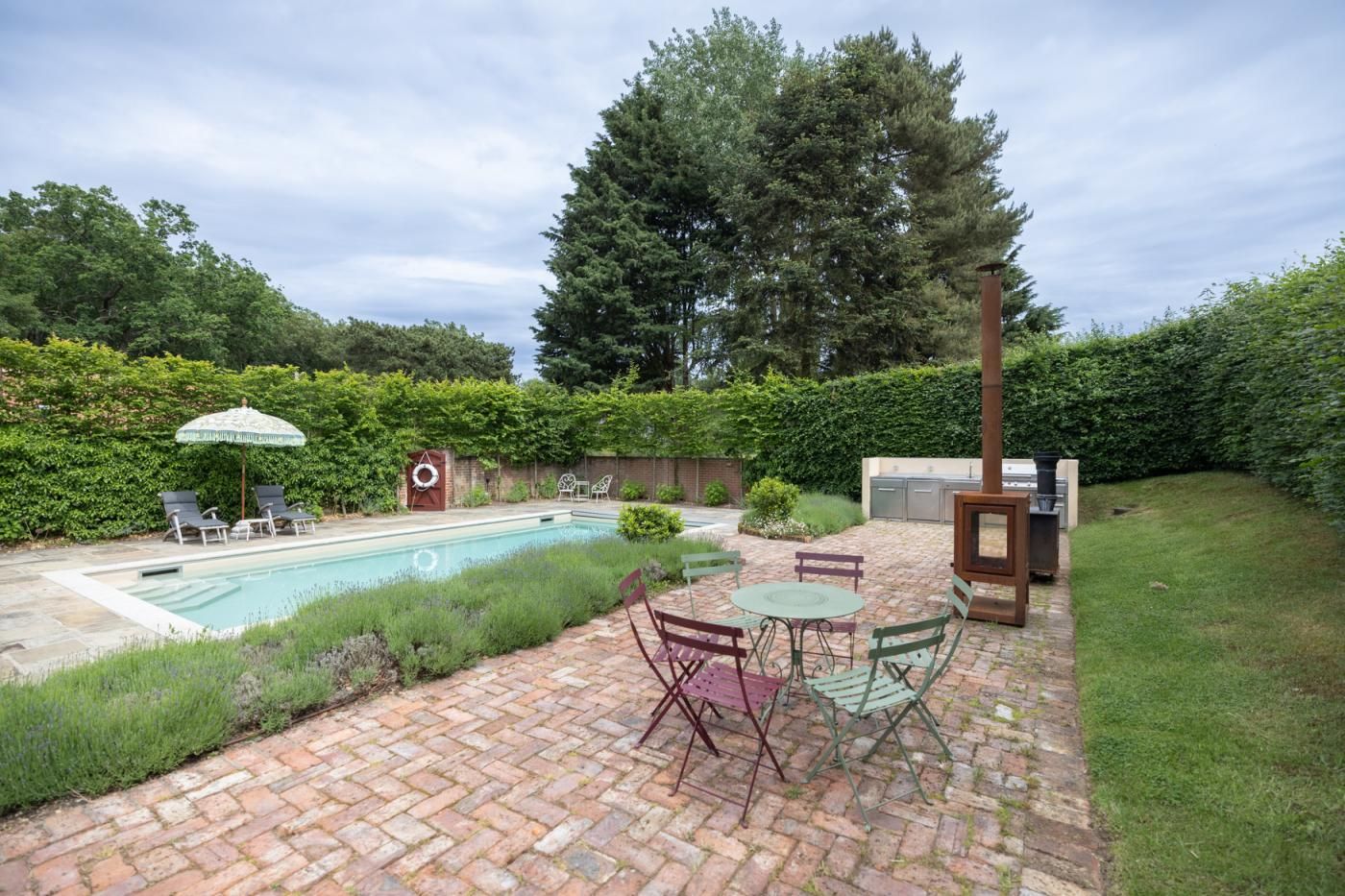 A backyard with a swimming pool, patio furniture, and a barbecue area.