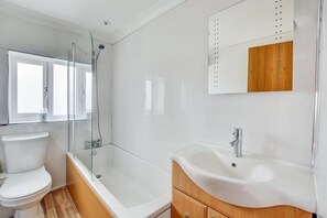 Une salle de bain moderne avec une douche à parois de verre, des toilettes blanches et un meuble-lavabo en bois avec un évier.