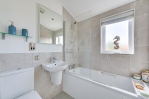 A modern bathroom with a bathtub, a sink, and a shower. There is a window with a decorative seahorse ornament. - 2 Bed in Burnham Market (oc-2335) (Burnham Market)