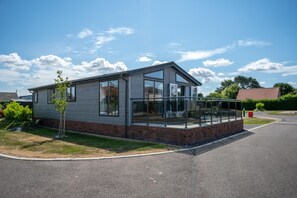 A modern two-story house with a glass balcony, a brick foundation, and a paved driveway. - 2 Bed in Burnham Market (oc-2335) (Burnham Market)