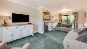 A living room with a fireplace, a television, and a sofa. - 3 Bed in Holt (oc-2280) (Holt)