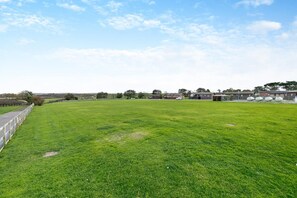 A grassy field with a fence, buildings, and a clear sky. - 2 Bed in St. Merryn (oc-p00673) (Saint Merryn)