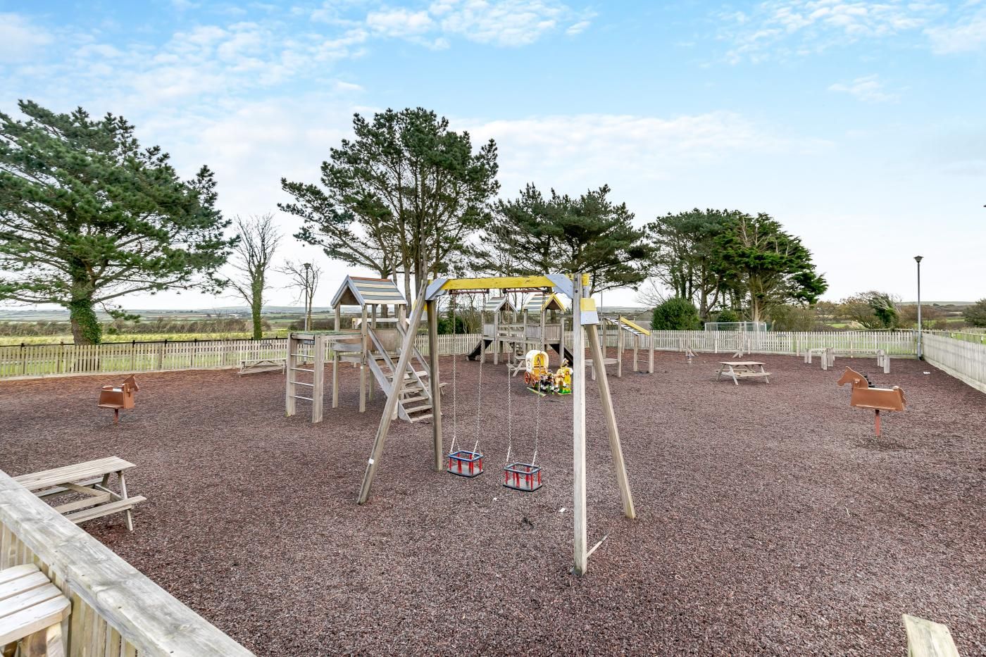 A playground with wooden structures, swings, and a slide.