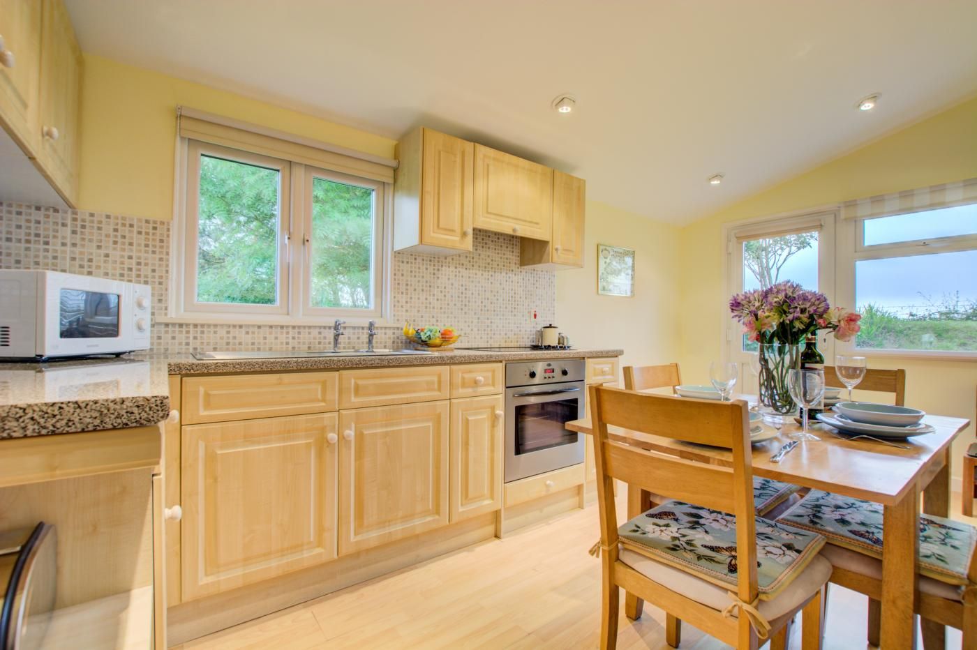 A kitchen with wooden cabinets, a microwave, an oven, and a dining table with chairs.