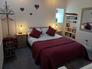 A bedroom with a bed, bedside tables, a wardrobe, a bookshelf, and decorative heart shapes on the wall. - 4 Bed in Low Row (oc-h34097) (Crackpot)