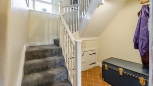 A staircase with white balusters, a dark-colored trunk with brass hardware, and a window with a white frame. - 4 Bed in Low Row (oc-h34097) (Crackpot)