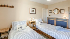 A bedroom with two beds, a bedside table with lamps, a dresser, and a coat rack. - 4 Bed in Low Row (oc-h34097) (Crackpot)