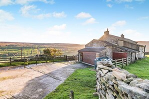 A stone house with a brick extension, a stone wall, and a grassy area with a paved path. - 4 Bed in Low Row (oc-h34097) (Crackpot)