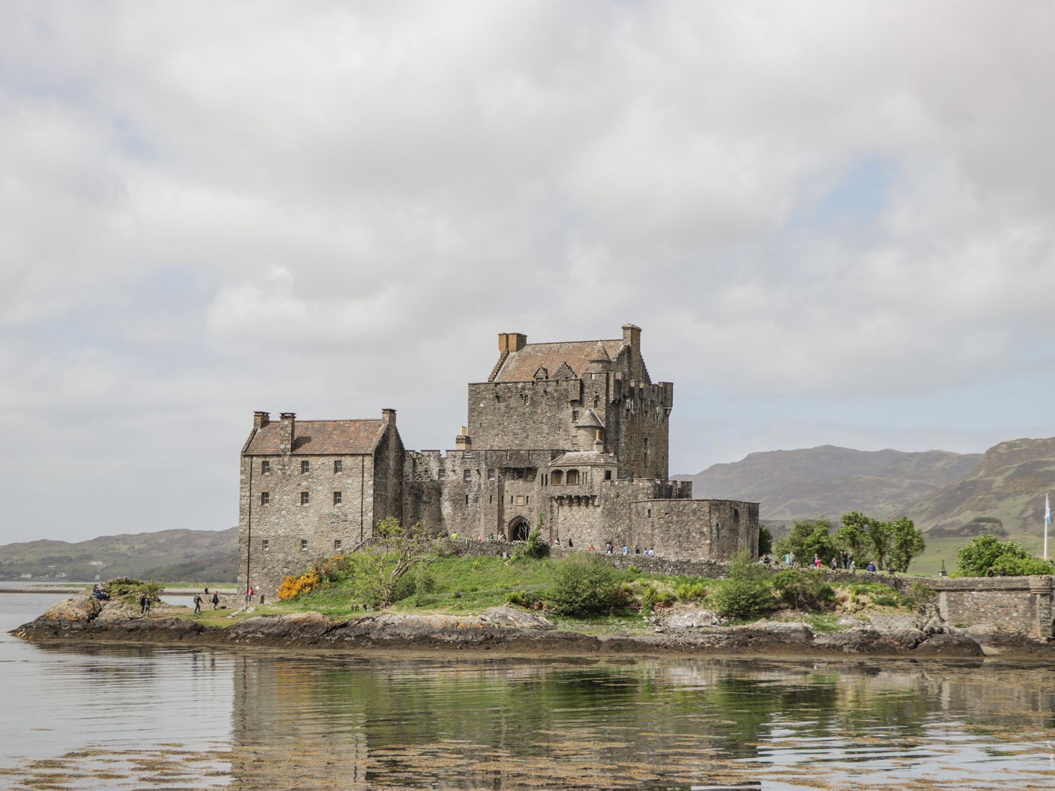 A historic castle with a large central tower, situated on a small island surrounded by water.