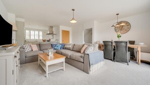 Ein modernes Wohnzimmer mit Sofa, Couchtisch und Essbereich.