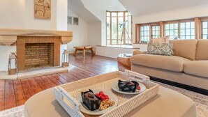 A spacious living room with a fireplace, a sofa, and a coffee table with snacks. - 6 Bed in Englefield Green (oc-e34166) (Englefield Green)