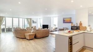 Un salon moderne avec des meubles en osier, un coin repas et une cuisine équipée d’un four à micro-ondes et d’un grille-pain.