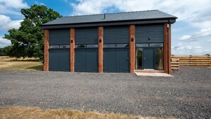 A modern building with a dark exterior, large garage doors, and a gravel driveway.