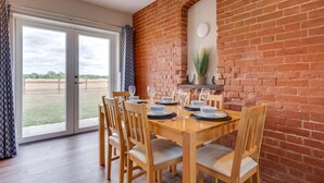 A dining area with a brick wall, a large window, and a view of an outdoor field.