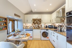 A modern kitchen with white cabinets, a built-in oven, a microwave, and a washing machine. - 1 Bed in Slaithwaite (oc-c34249) (Ripponden)