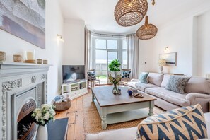 Ein geräumiges Wohnzimmer mit Kamin, Fernseher, Sofa und Couchtisch.