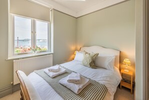 Ein Schlafzimmer mit einem Bett, Nachttischen, einem Fenster mit Blick und einer Heizung.