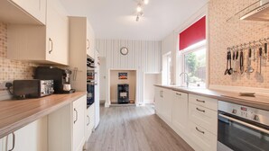 A modern kitchen with white cabinets, a Bosch oven, and a coffee machine. - 5 Bed in Runswick (oc-wa326) (Runswick Bay)