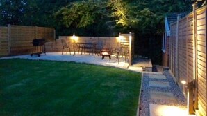 A backyard with a barbecue area, outdoor seating, and a stone pathway leading to a wooden gate. - 5 Bed in Runswick (oc-wa326) (Runswick Bay)