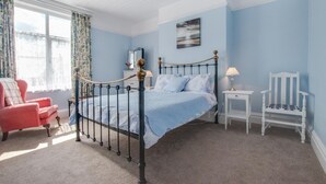 A bedroom with a bed, a chair, a nightstand, and a window with curtains. - 5 Bed in Runswick (oc-wa326) (Runswick Bay)