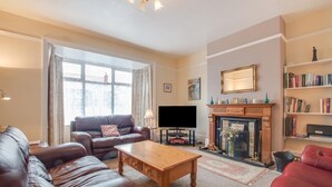 A living room with a fireplace, leather sofas, a coffee table, and a bookshelf. - 5 Bed in Runswick (oc-wa326) (Runswick Bay)