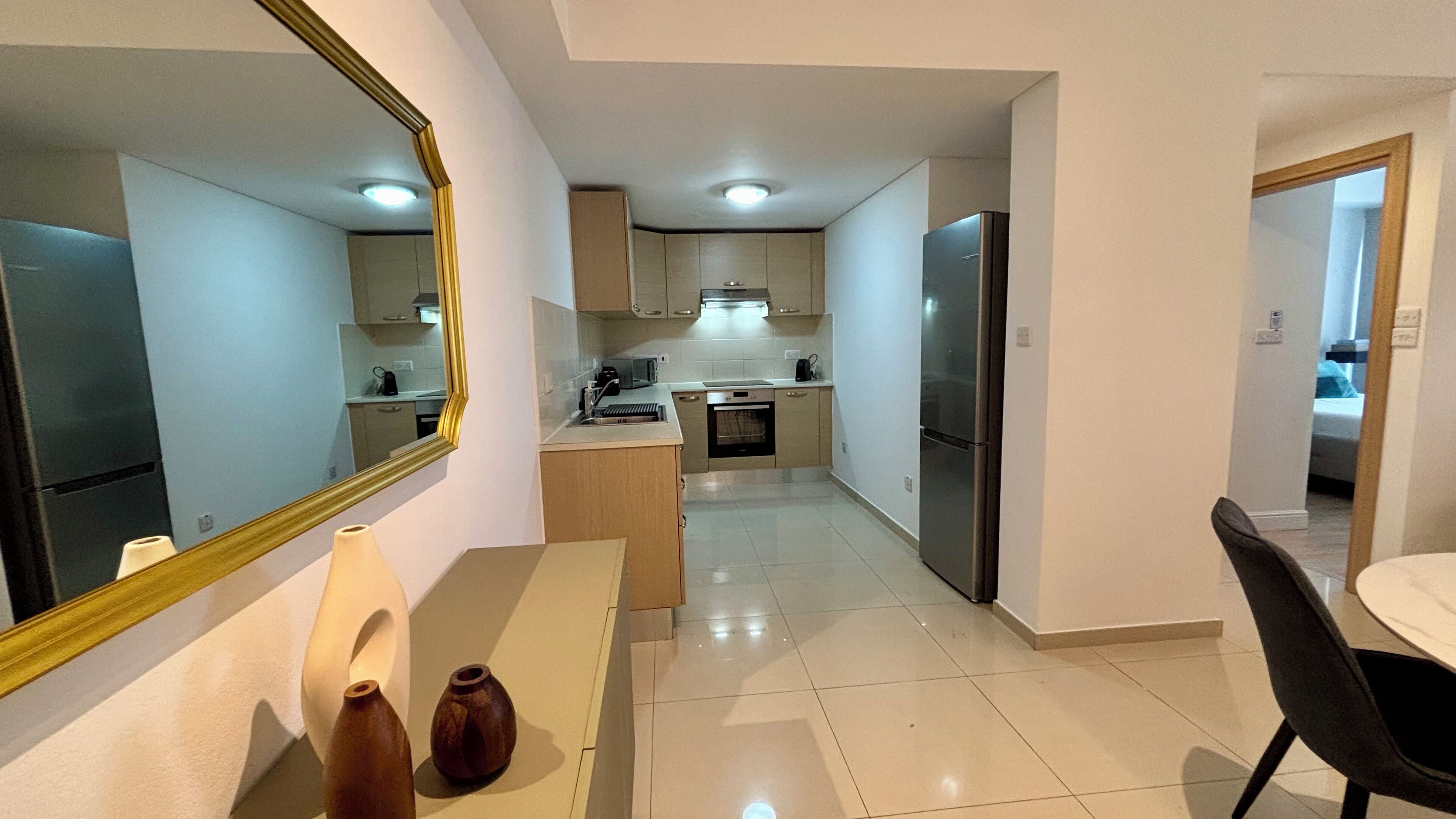 A modern kitchen with a central island, a dining area with a table and chairs, and a large mirror on the wall.