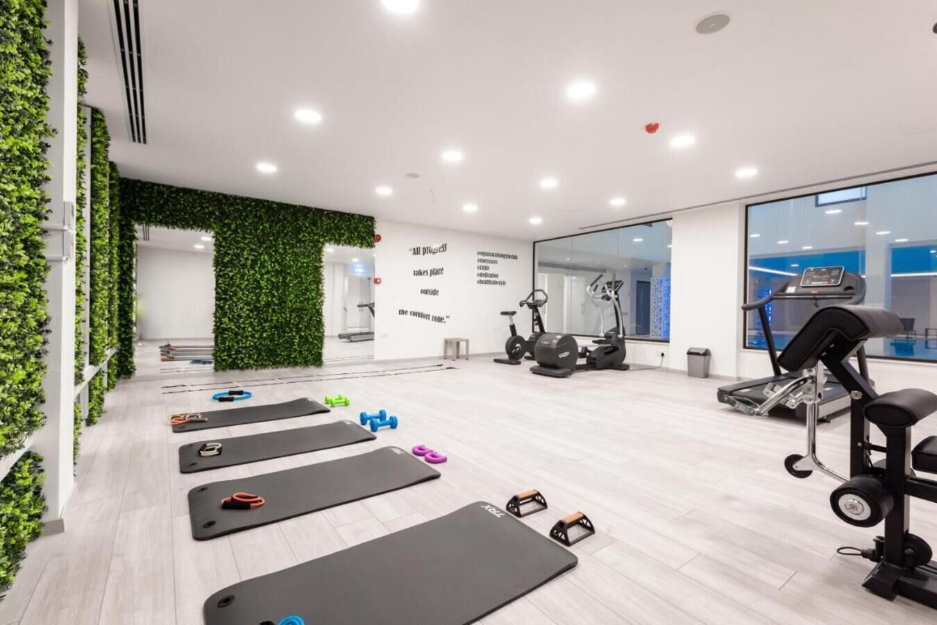 A modern gym with exercise mats, weights, and cardio equipment.