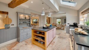 A spacious kitchen with a central island, grey cabinetry, and a wooden ceiling beam. - 5 Bed in Scalby (oc-sa871) (Scalby)