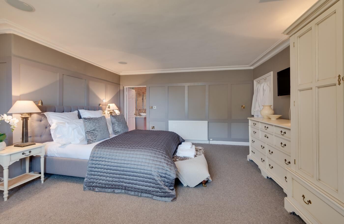 A bedroom with a bed, bedside tables, a dresser, and a walk-in closet.