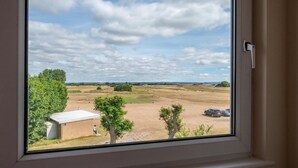 A view from a window overlooking a rural landscape with open fields, a few trees, and a parked car. - 3 Bed in Littlestone (oc-bt009) (Littlestone)